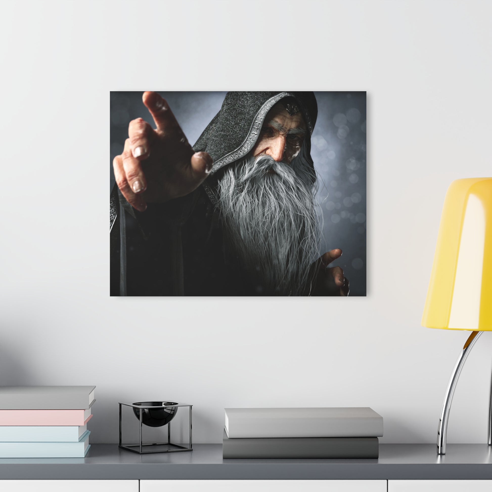 A framed wall art print showing a hooded wizard with a long white beard pointing forward, displayed above a shelf with books and a yellow lamp in a modern room setting.