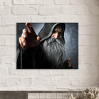 A rectangular wall art print showing a close-up portrait of an elderly wizard or sorcerer with a long gray beard, dark hood, and outstretched hand, mounted on a white painted brick wall above a mantel.