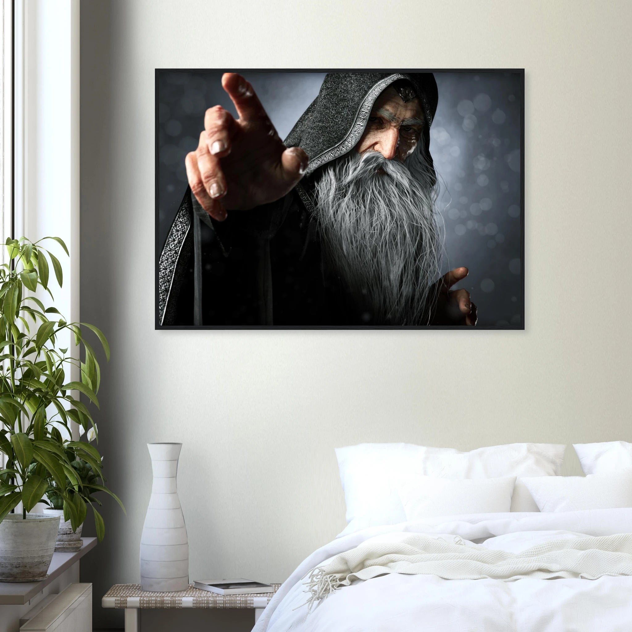 A framed wall art print depicting a hooded figure with a long gray beard pointing forward, displayed above a bed in a modern bedroom setting with a plant and vase.