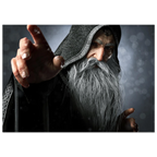 A rectangular wall art print showing a close-up portrait of an elderly wizard or sorcerer with a long white beard, dark hooded robe, and one hand raised forward, set against a smoky gray background.
